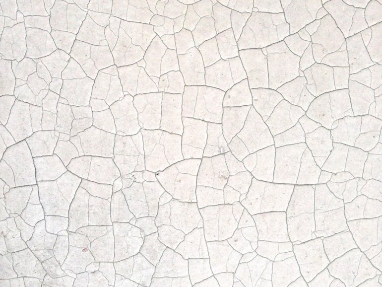 a close up of a white wall with cracks in it